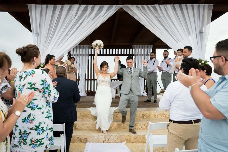 Newlyweds hands in the air after ceremony