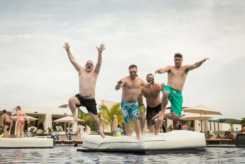 Groomsmen jumping into swimming pool